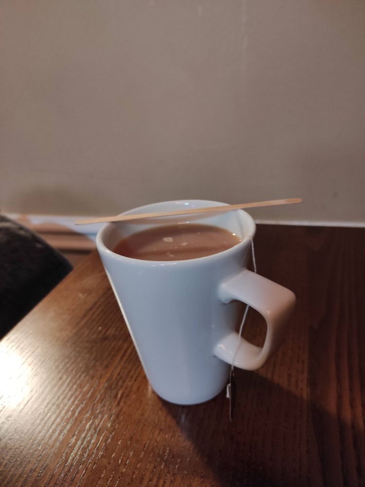 A white wetherspoons mug full of tea on a brown wetherspoons table against a beige wetherspoons wall