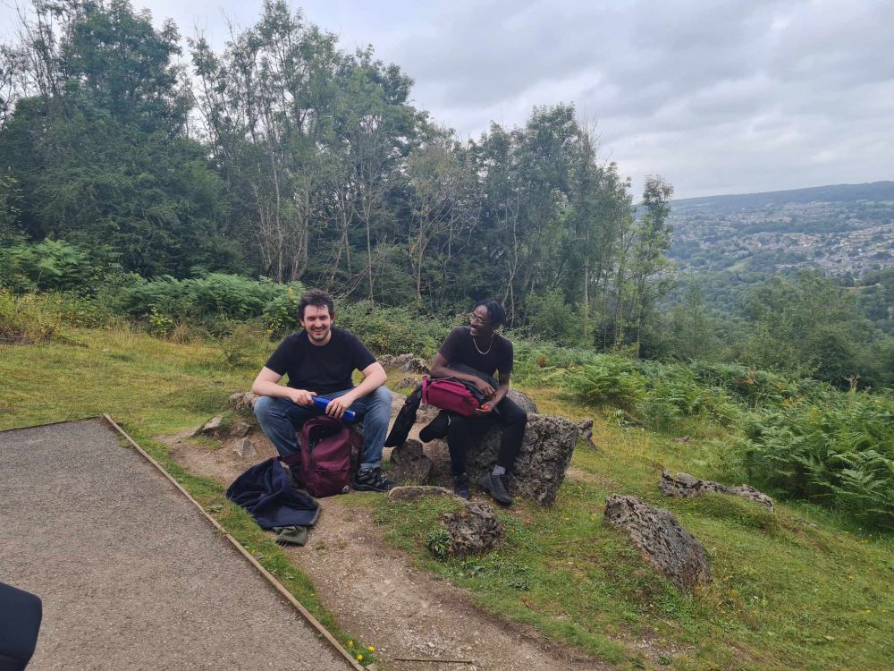 Alex and Chavonne on top of a hill, sitting on rocks in the peak district