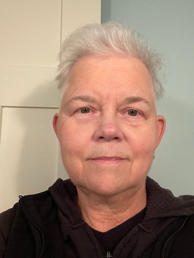Selfie showing off my new haircut. Shaved sides and pretty short on top. Still grey, since I can’t risk the perfume in my usual dye to change it back to its normal purple.