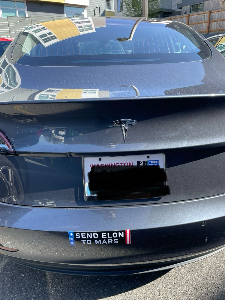 Rear is a Tesla car with a bumper sticker that reads, “SEND ELON TO MARS.”