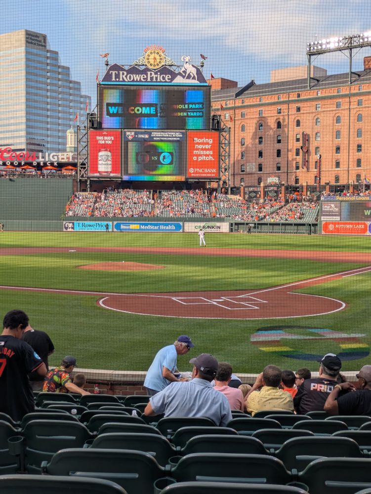 Camden Yards, with an Orioles Pride logo behind the plate and graphics on the screens.