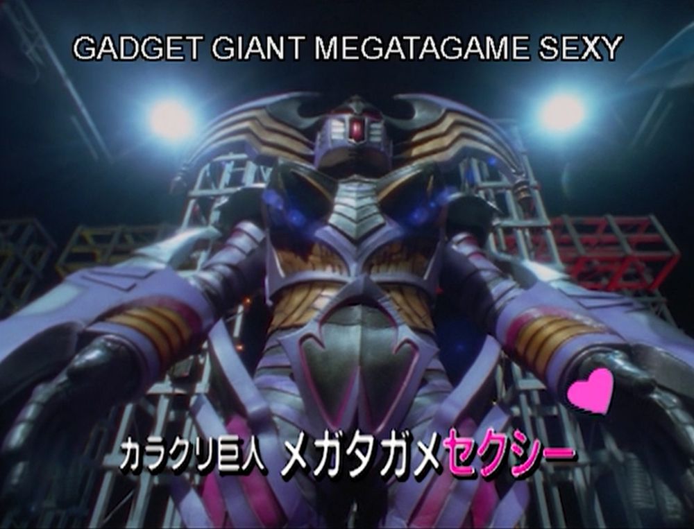 A shot of the giant mech again with the subtitle GADGET GIANT MEGATAGAME SEXY and a bright pink heart next to it