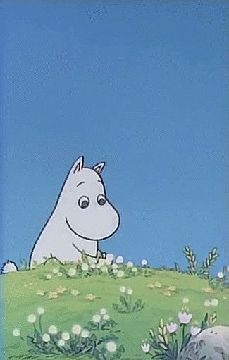 A photo from the animated 90s Moomin series, showing Moomin on a flower hill picking flowers. The sky is blue and free of clouds.