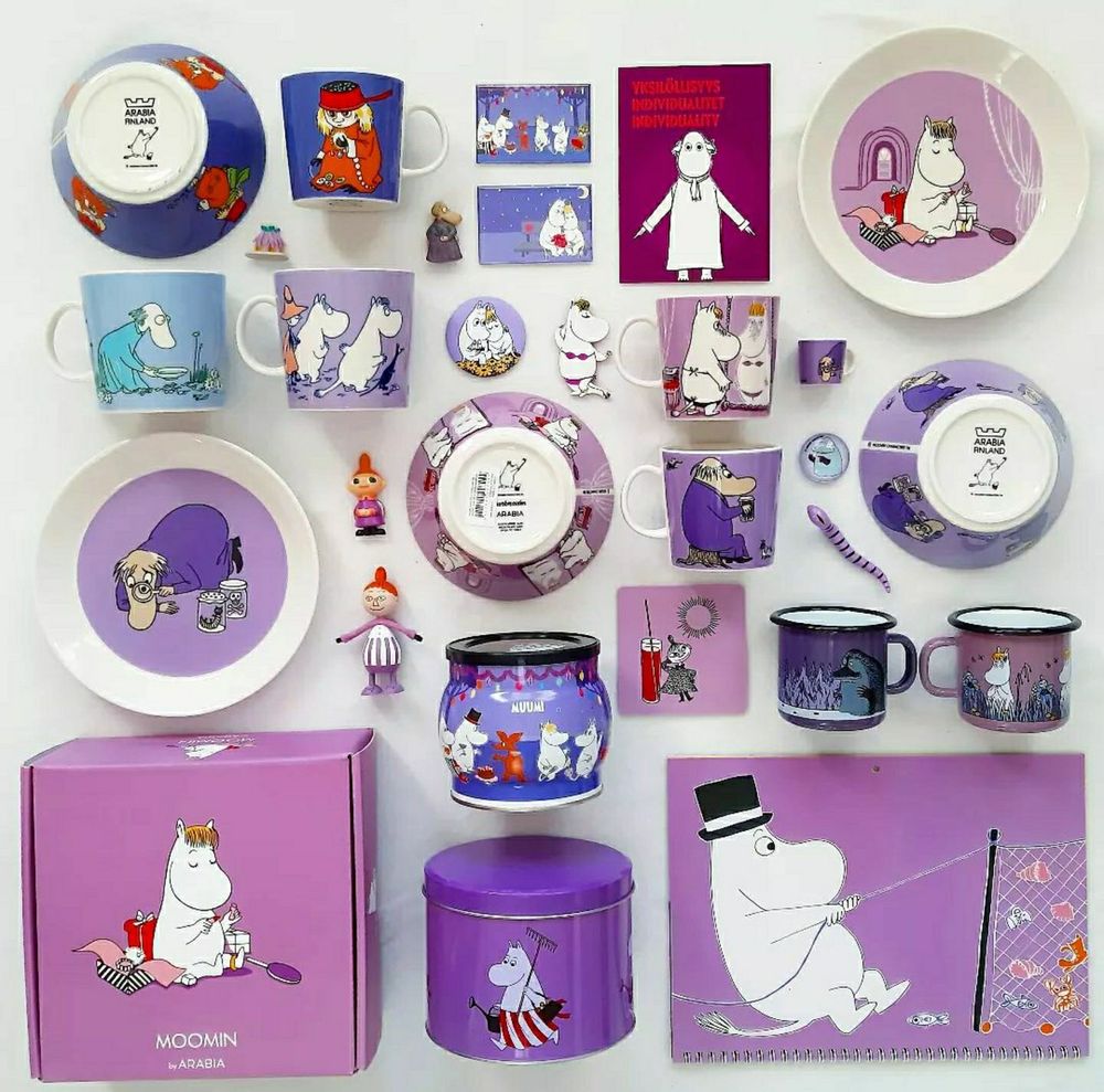 A photo of several Moomin cups, boxes, a cutting board, plates and wall magnets. All in the colour purple. They show many characters — Hemulen, Moomin Pappa, Snork Maiden, Moomin Mamma, the Groke, little My and Too Ticky.