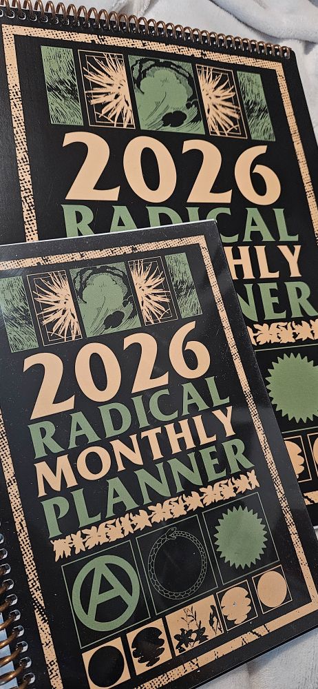 Photo of a ring-bound A5 monthly planner and an A4 ring-bound calender — both for the year 2026. Both covers are identical and read "2026 radical monthly planner" in alternating yellow and green colours, above and below the text are varying pannels with visual textures and patterns also in yellow and green. Three pannels stick out as they show an anarchist circled A symbol, an uroboros snake (snake eating it's tail in a circle), and many-spiked star (small spikes). 