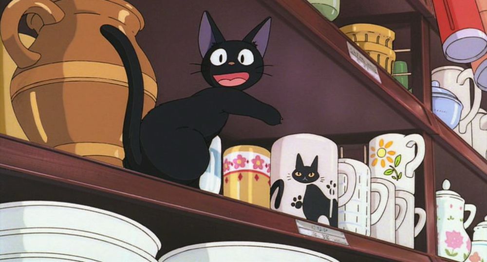 Gigi from Kiki’s Delivery Service pointing at a mug with a black cat on it