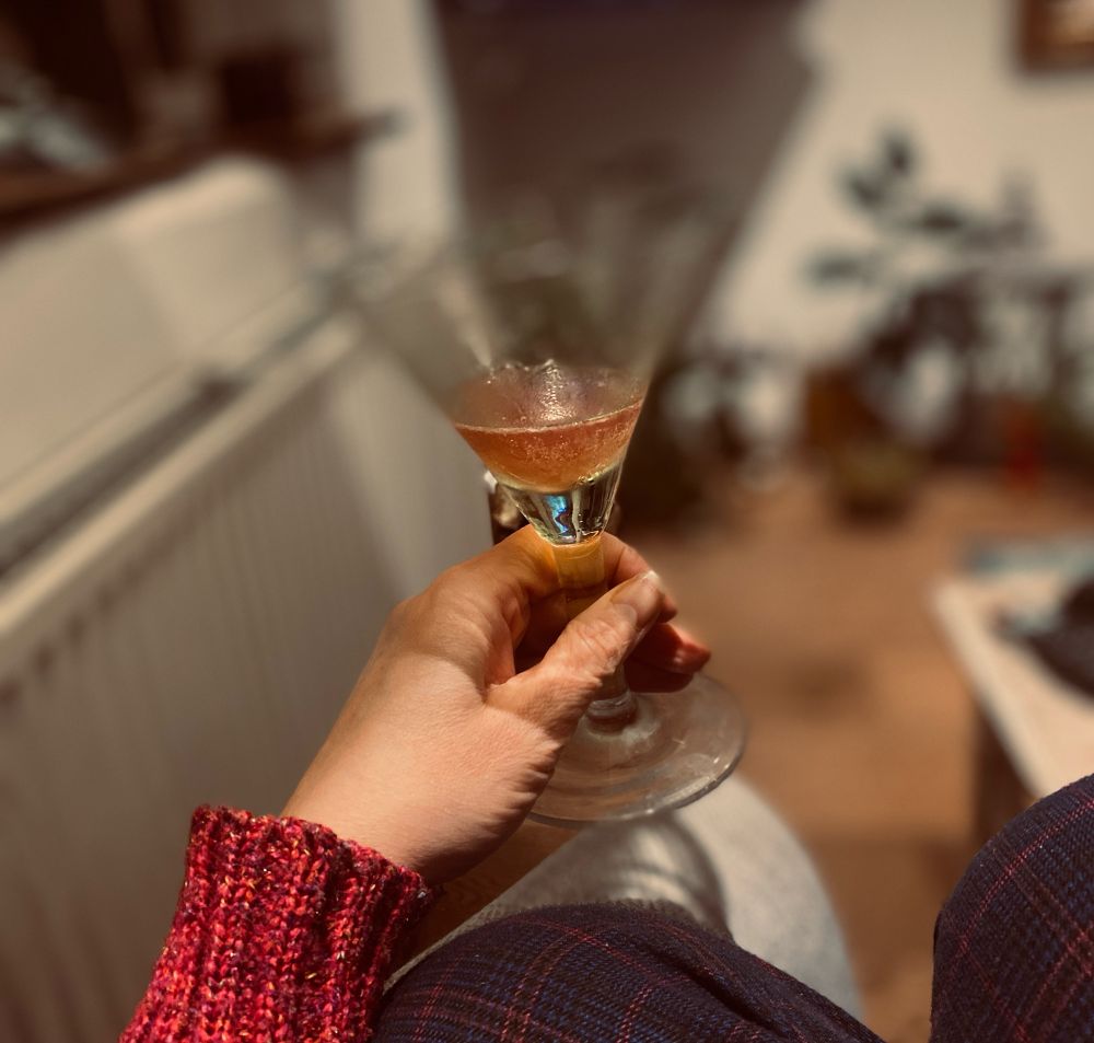A mostly devoured Cosmopolitan cocktail is being held in a cocktail glass.