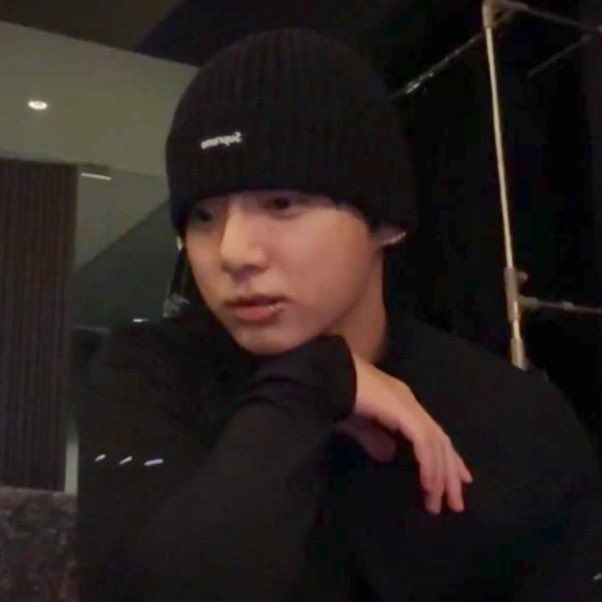 Jungkook in a beanie with a hand under his chin