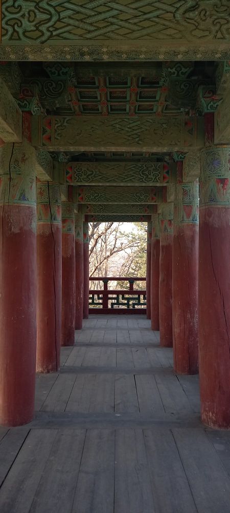 붉게 칠한 나무 기둥이 2열로 나란히 서있고 그 사이로는 건물 밖 풍광이 드러나 보인다