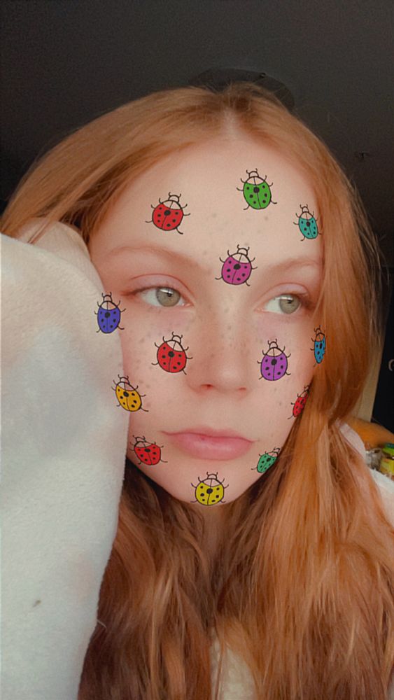 a picture of me, my hair is down and draped over my shoulders and i have the colourful ladybug snapchat filter on my face 