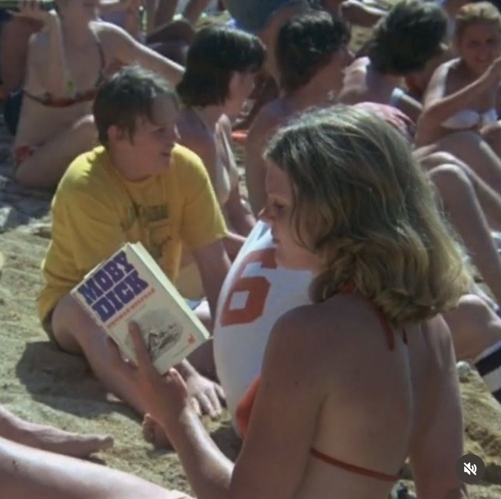 a girl on the beach reading moby dick 