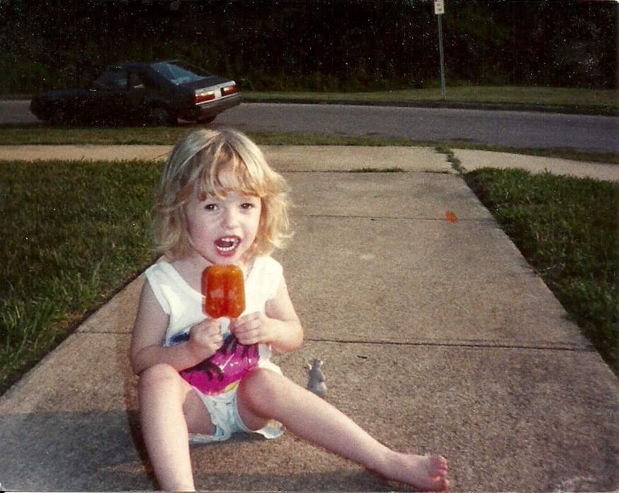 Me at like, 2? Eating a huge orange popsicle while sitting on a sidewalk 