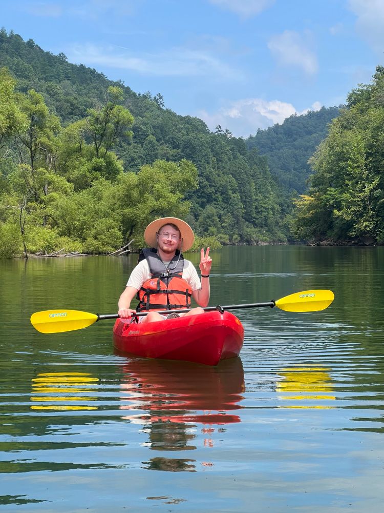 Photo of me while kayaking. I’m holding a peace sign up 