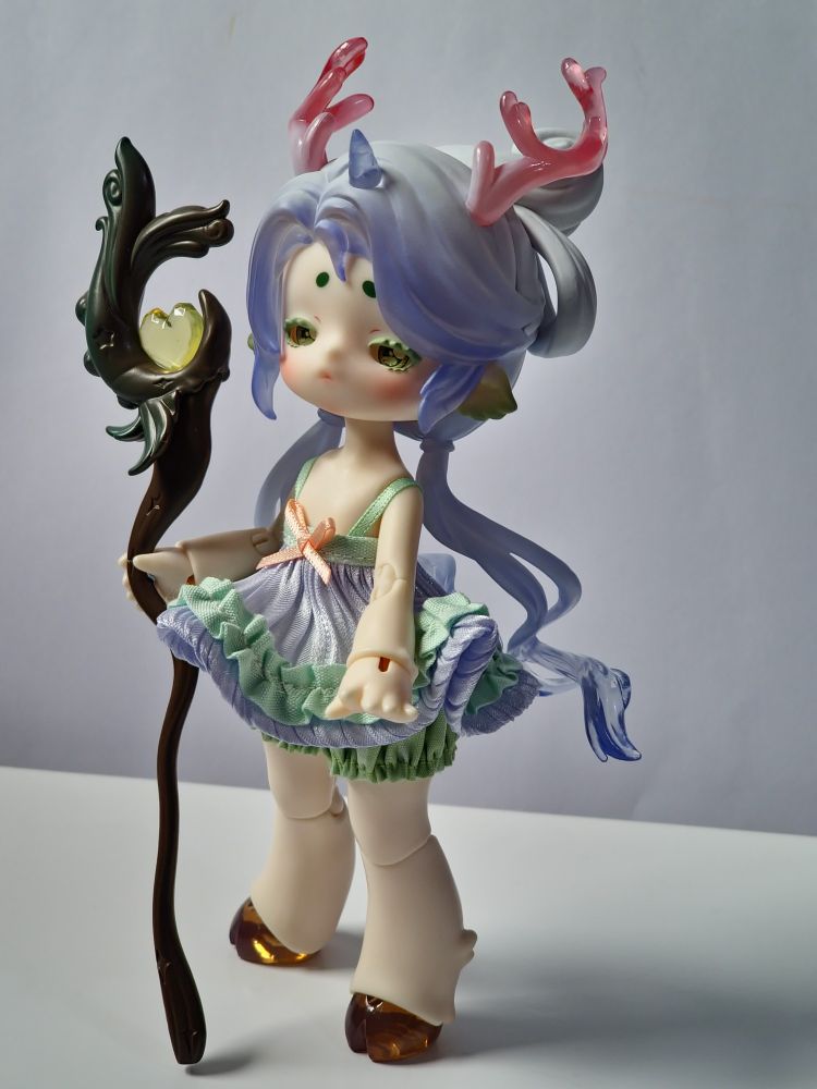 Another haughty looking ball jointed doll in soft pastel tones of pink, purple and green. They have large hands and feet with sculpted fur-like details on wrists and ankles. Their 5 point deer-like horns are deep, transparant pink curves. They have brown semi transparent hooves. They are holding a curvy staff set with a jewel.
It's made from a combination of Penny's Box cute beasts, nine coloured deer and dreamlike tea party.