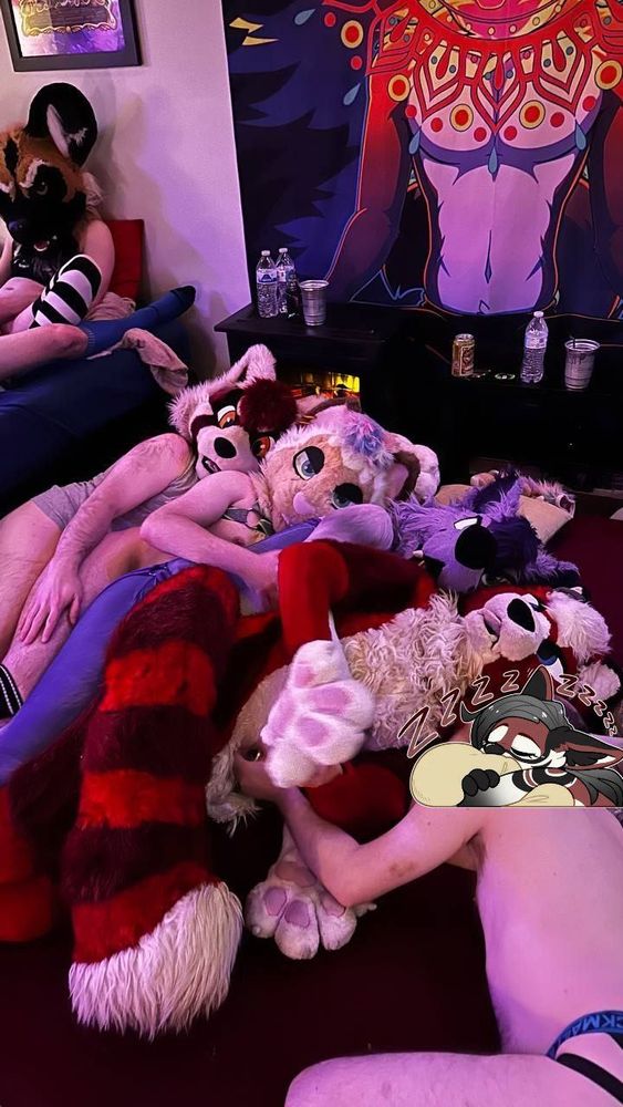 four fursuiters all spooned together on the floor, most looking at the camera