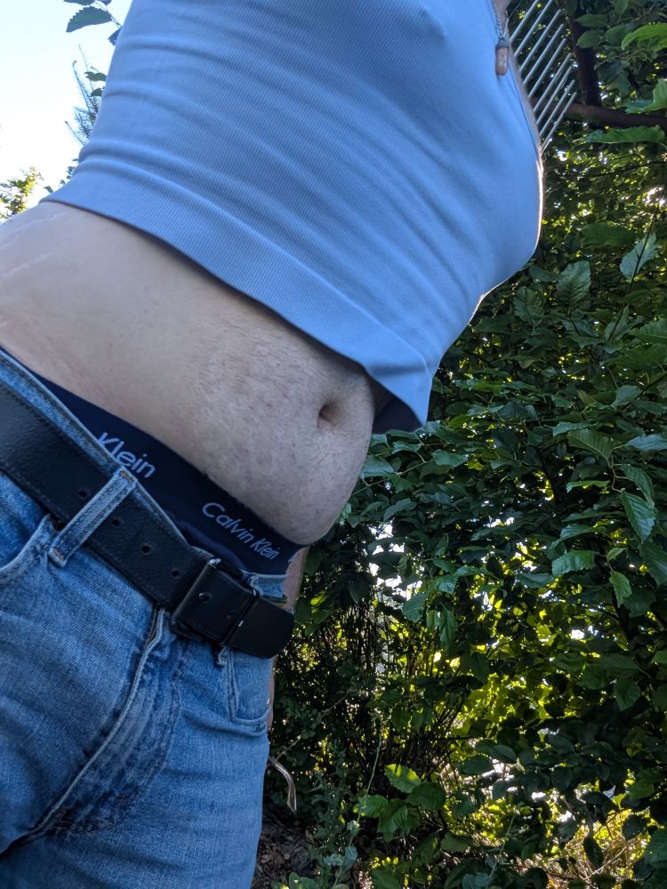 photo of me wearing a tight, light blue cropped tank top. my midriff is exposed, and my jeans are pulled down maybe an inch so you can see the elastic band on my navy blue undies.