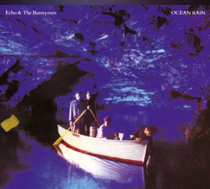 Album cover for Ocean Rain by Echo and the Bunnymen. The band members are depicted in a rowboat in a blue cavern