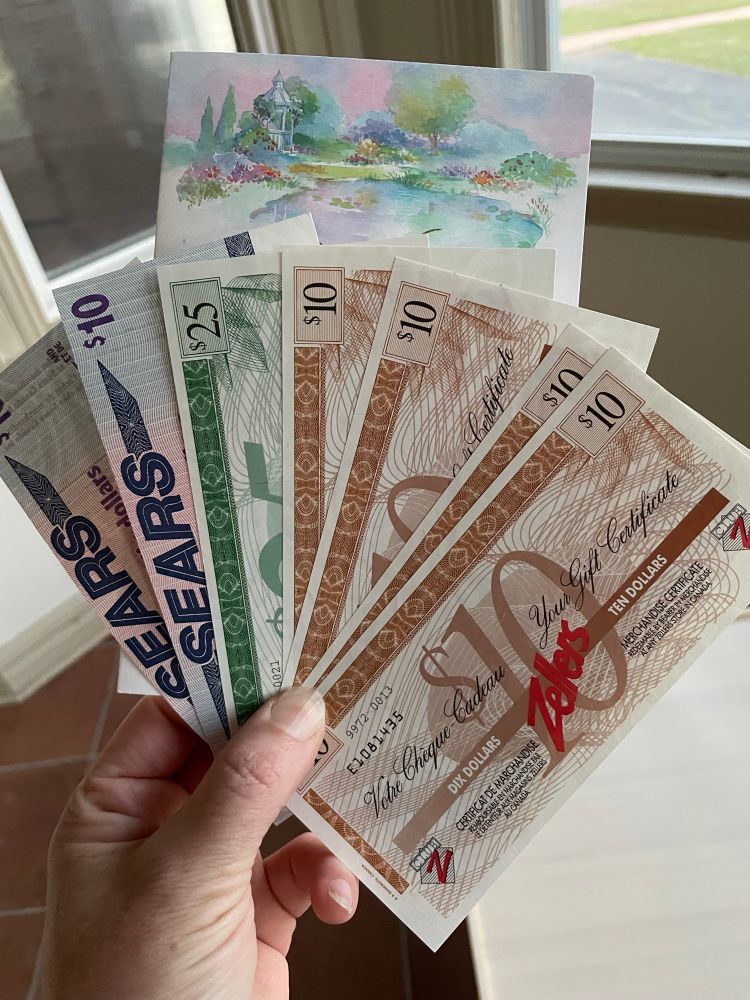 My hand holding $85 in Zellers and Sears paper money that people paid real money for in 2002. 