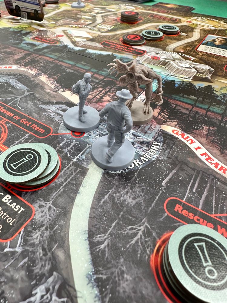 Stranger Things board game, the miniatures of Lucas and Hopper face off against a miniature Demogorgon.