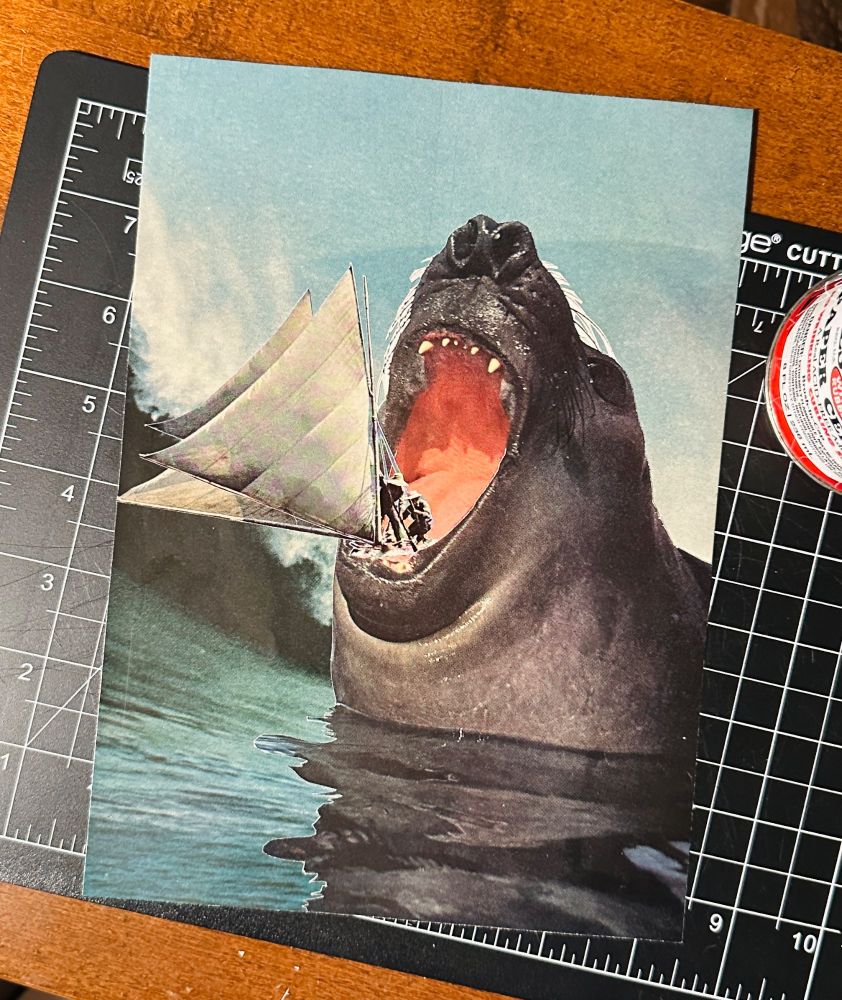 Analog collage, large wave in the background and an unrealistic sized seal with a sailboat it its mouth (two passengers).
