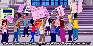 Still from Bob’s Burgers with Linda Belcher leading museum picketers in a chant, “Give us more money, damn it! Or we’ll shave the wooly mammoth!”
