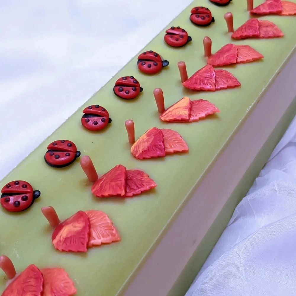 Green apple soap loaf topped with red leaves and ladybugs gives the fall vibes 