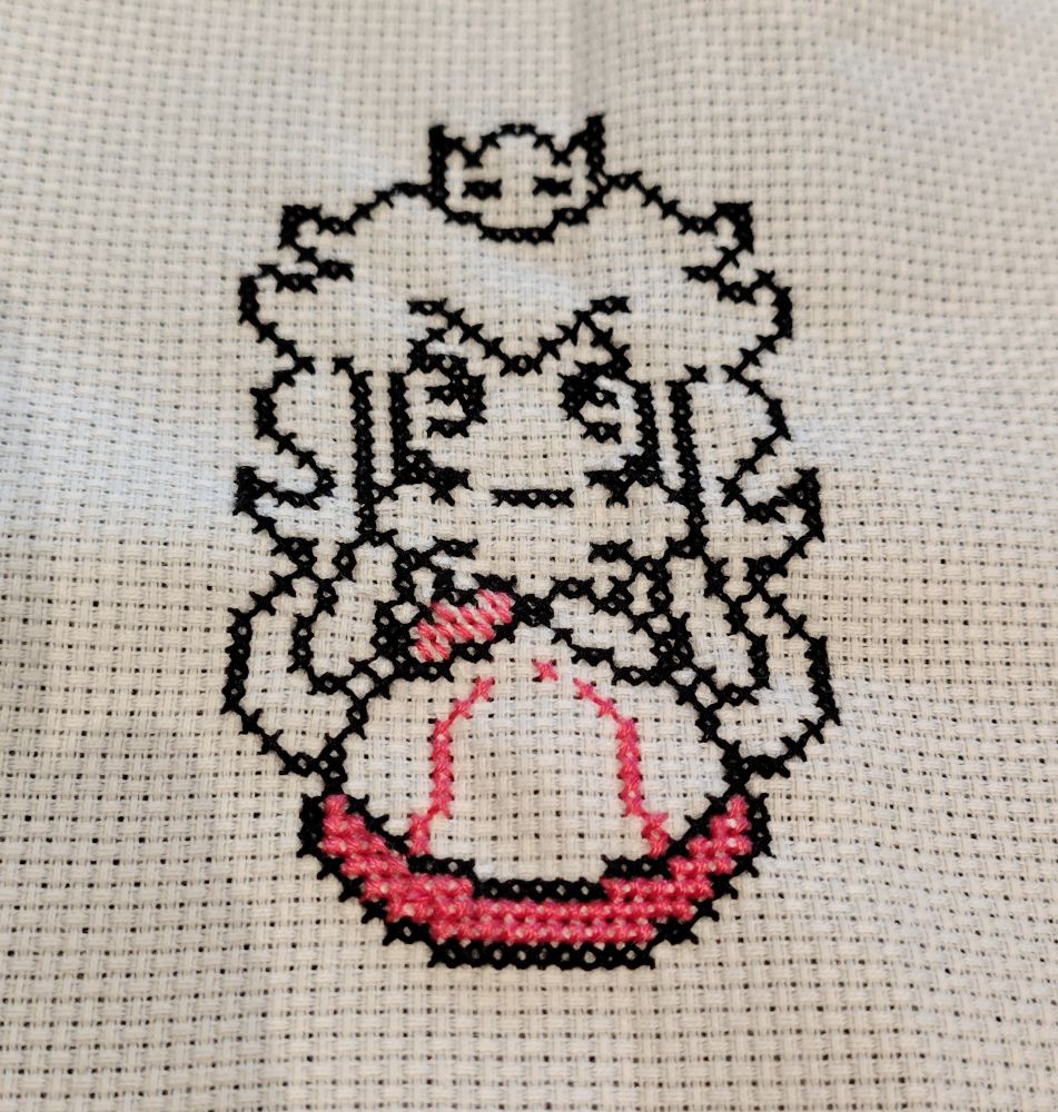An unfinished cross stitch of Princess Peach. It's a black outline with a touch of colour. Black floss on white aida 