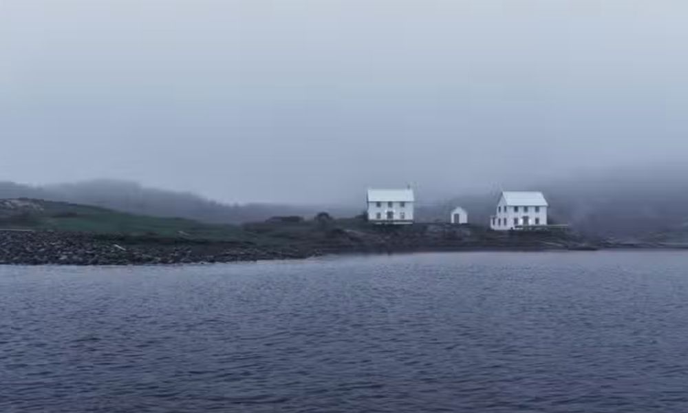 2 large white houses on a desolate island. The area is foggy.