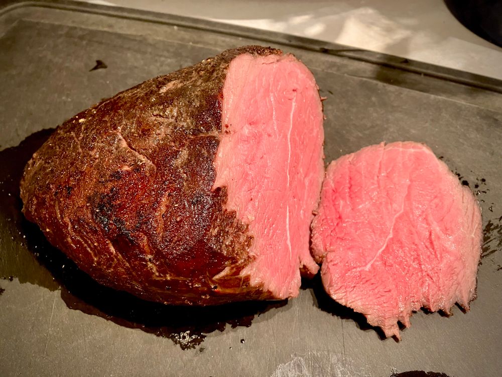 A beef roast cooked for 20+ hours in the sous vide and then browned with a Searzall torch. This pic shows the roast on a cutting board with the first slice made - the roast is edge-to-edge medium rare on the inside and browned and seared on the outside