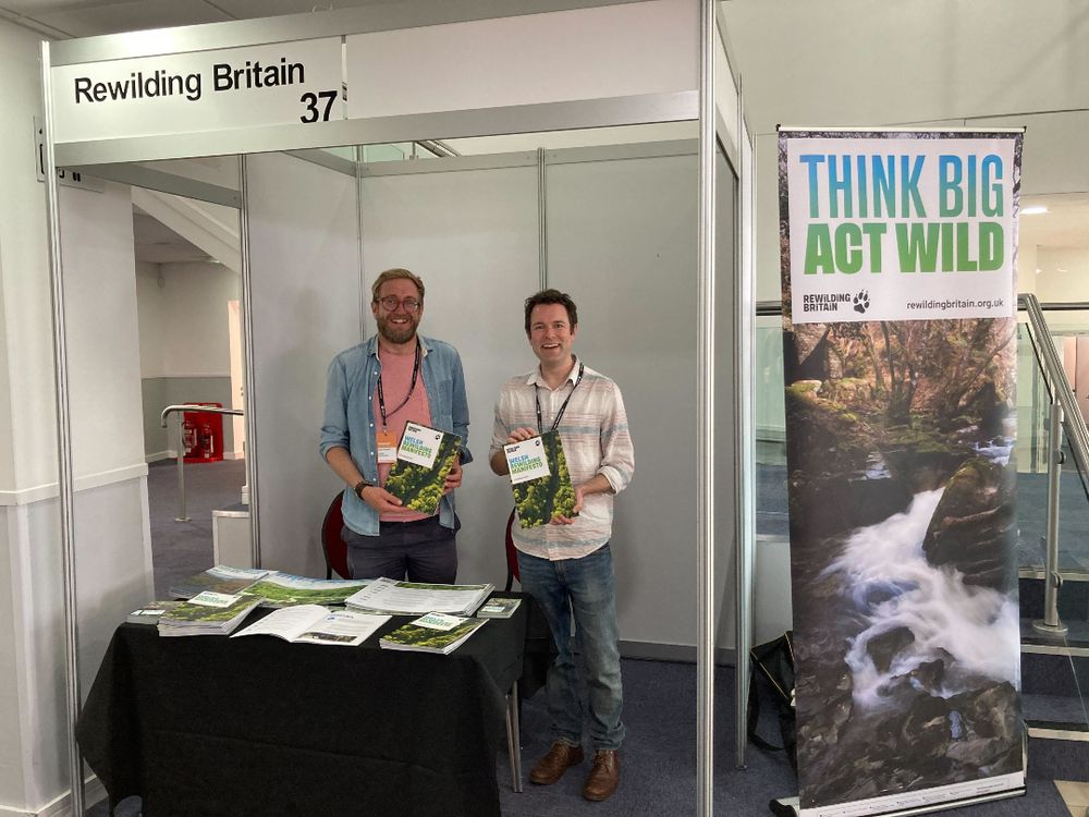 Photo of Rewilding Britain's James Hitchcock and Ollie Newham in front of a stand at the Welsh Labour Party conference.