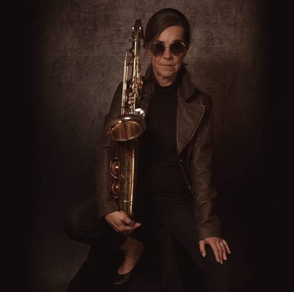 Eine Frau mit einem Saxophon im Arm
