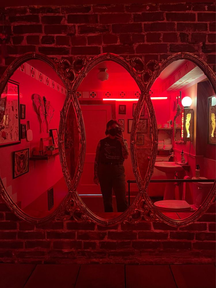 Mirror selfie with red neon light and brick wall