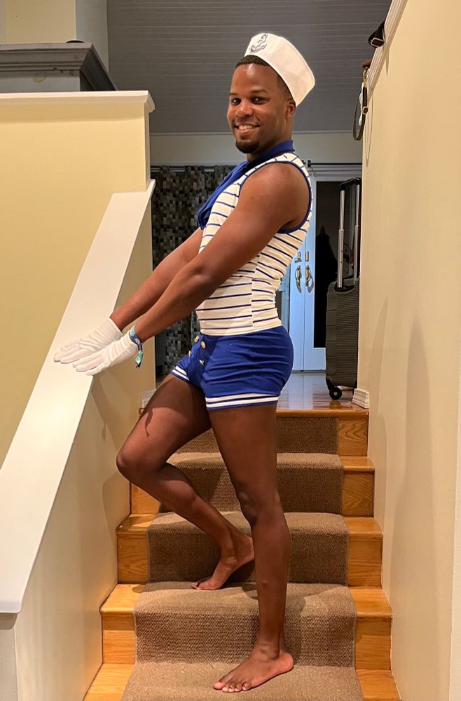 Electro wearing a sailor costume and posing on a staircase