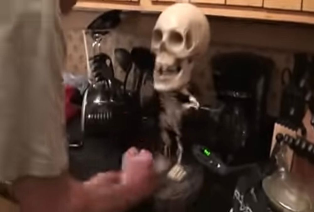 The man frustratedly beats the toy skeleton.