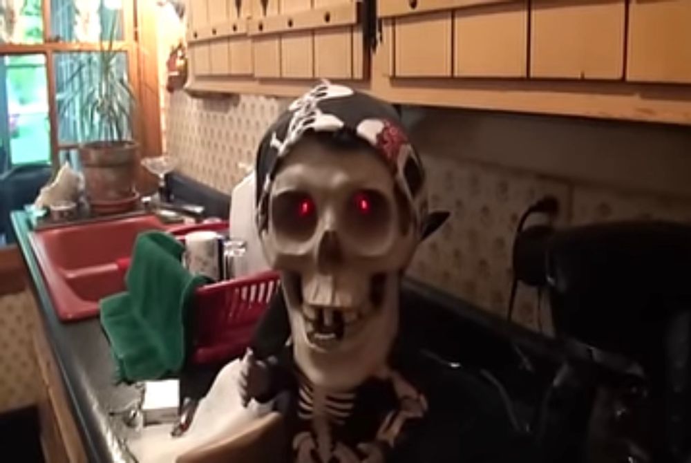 A plastic skeleton in a kitchen, red eyes.