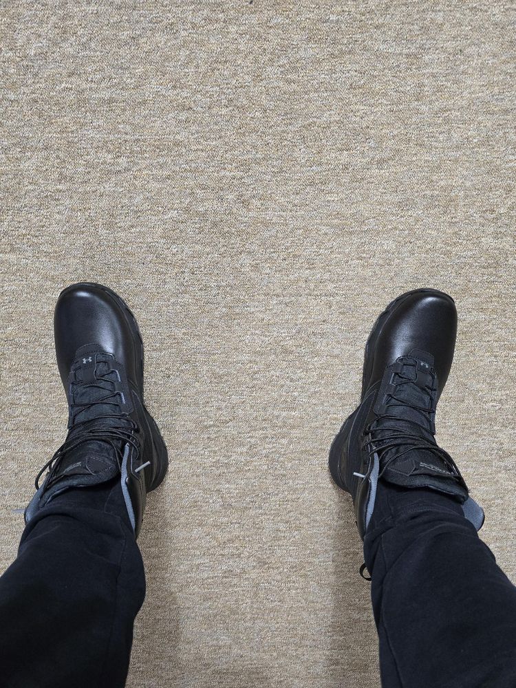 A man's legs wearing Under Armour Stellar G2 tactical boots + black joggers on carpet 