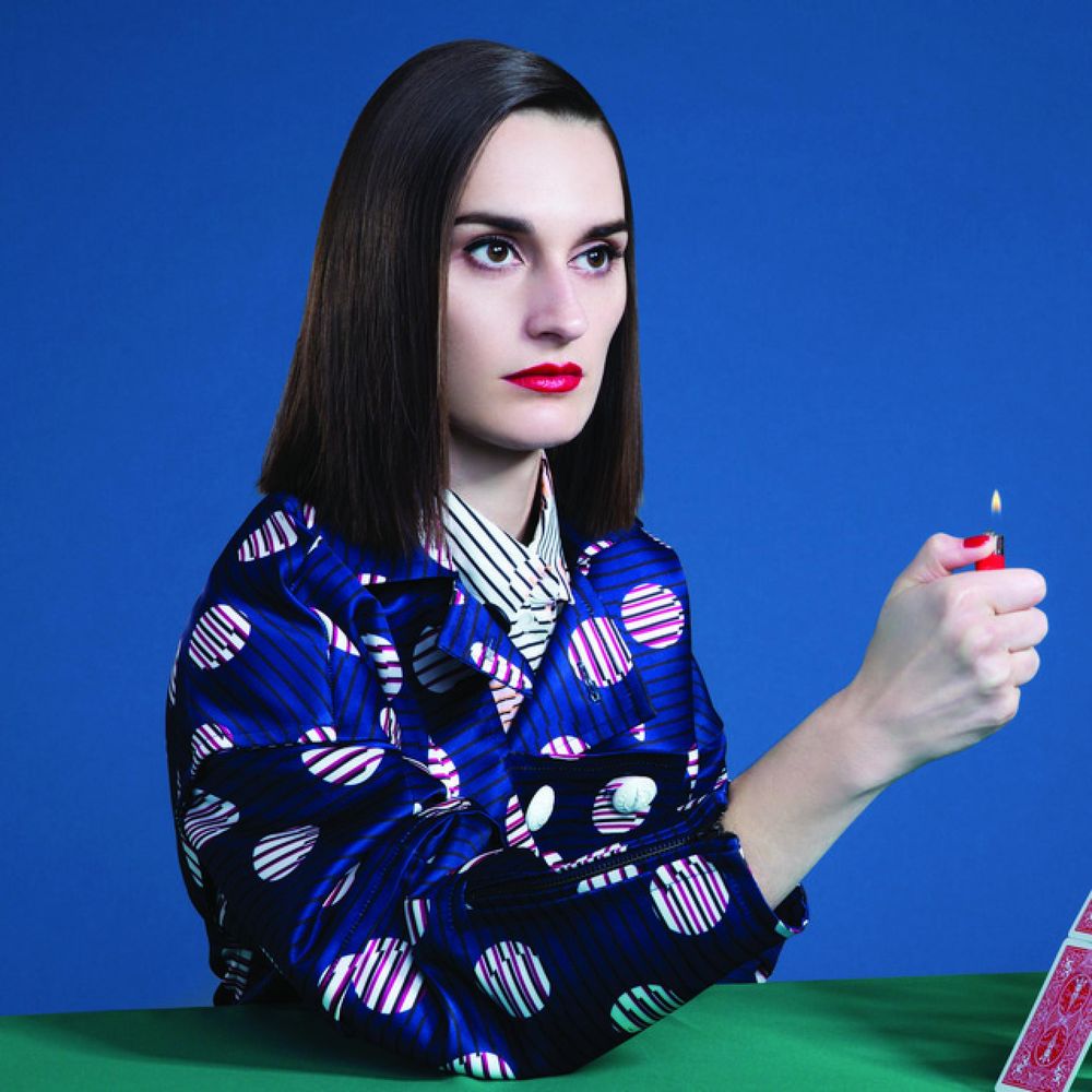 Brunette woman in kimono with cigarette lighter held up to house of cards 