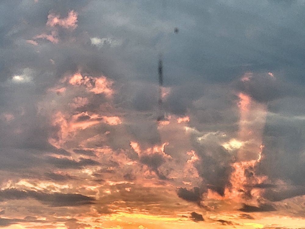 An early sunrise sky through a window with red rays beaming through morning clouds of the dawn.