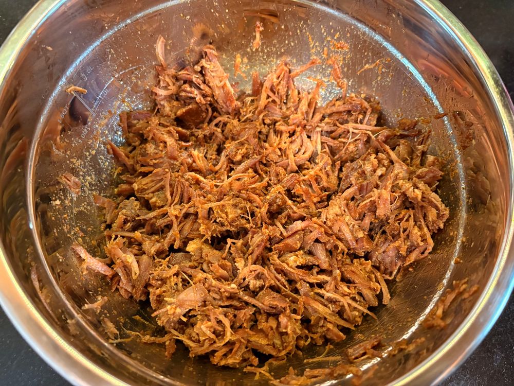 a metal bowl containing dry-rubbed, slow cooked pulled pork