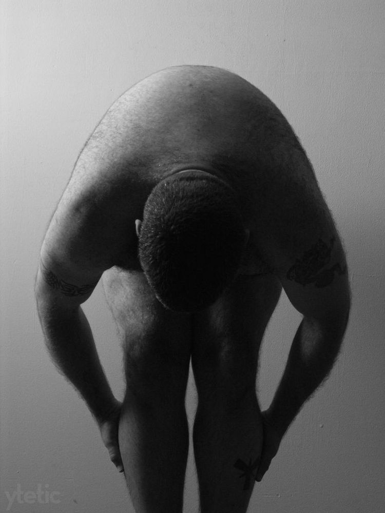 2. Facing us, bent forward at the waist, hands on calves.