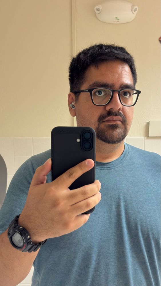 A picture of myself with my phone in hand, a watch and Thick rimmed glasses 