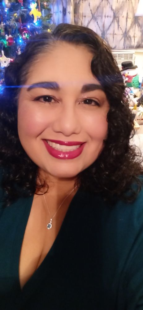 Mexican lady wearing a teal top and rocking hot pink lipstick. 