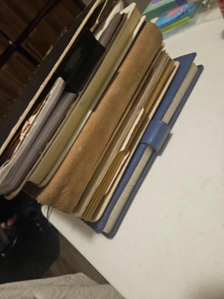 A stack of different notebooks and journals on a white table. 