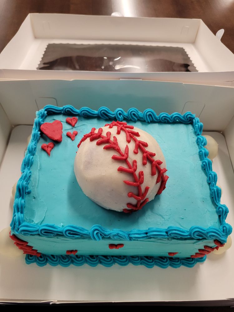 Blue cake with a baseball shape on top and hearts around it.