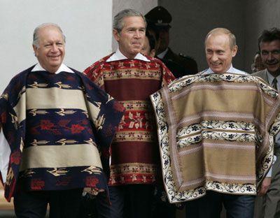 From left to right: Chilean President Ricardo Lagos, George W Bush, and Vladimir Putin stand next to each other wearing chamantos, a type of Chilean ponchos. (Reuters, 2004)