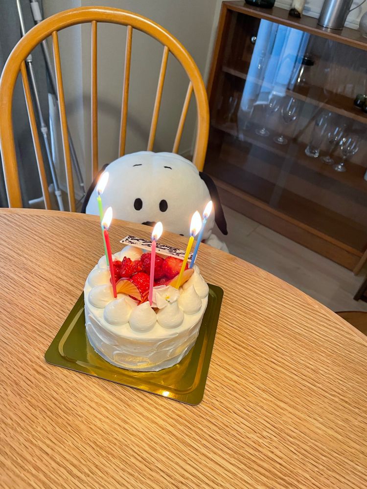 ろうそくのついたケーキを見つめるスヌーピー風ぬいぐるみ