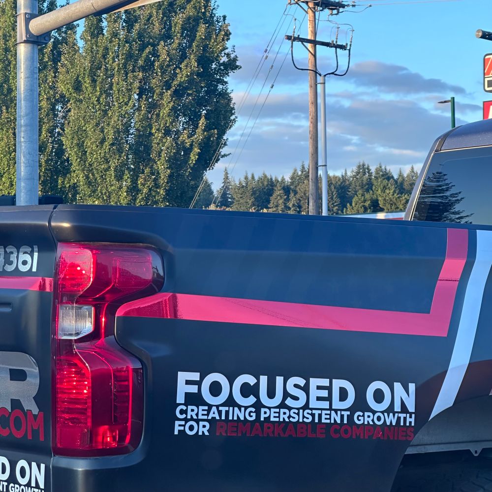 A pickup truck with a business advertisement on its side is shown. The ad reads:
“FOCUSED ON CREATING PERSISTENT GROWTH FOR REMARKABLE COMPANIES” in bold white and red letters.