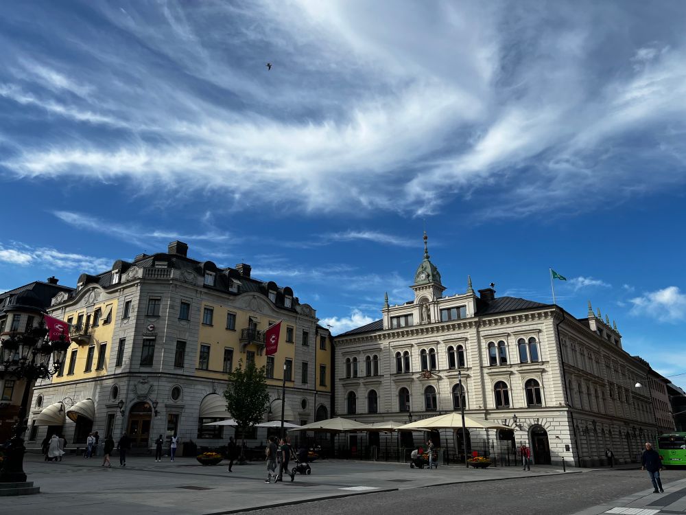 Light coloured buildings against blue skies with swirly clouds