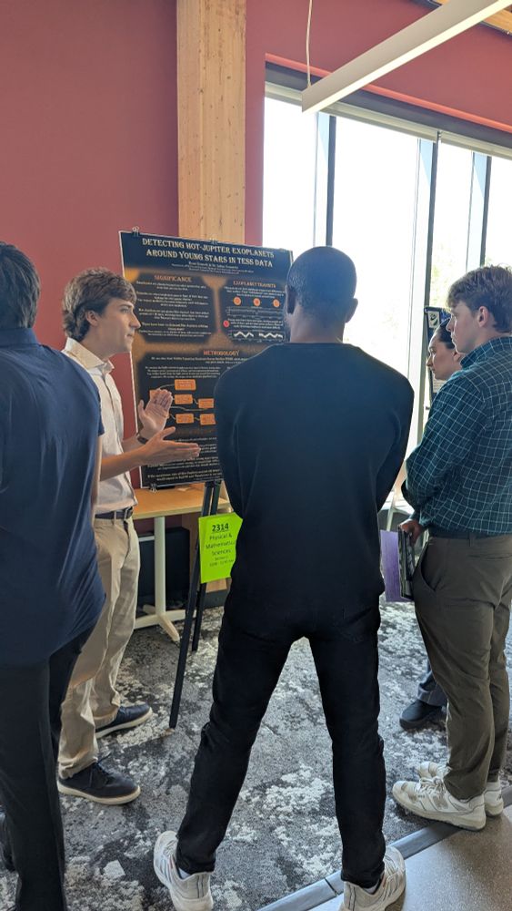 Undergraduate student talking to three people at their research poster