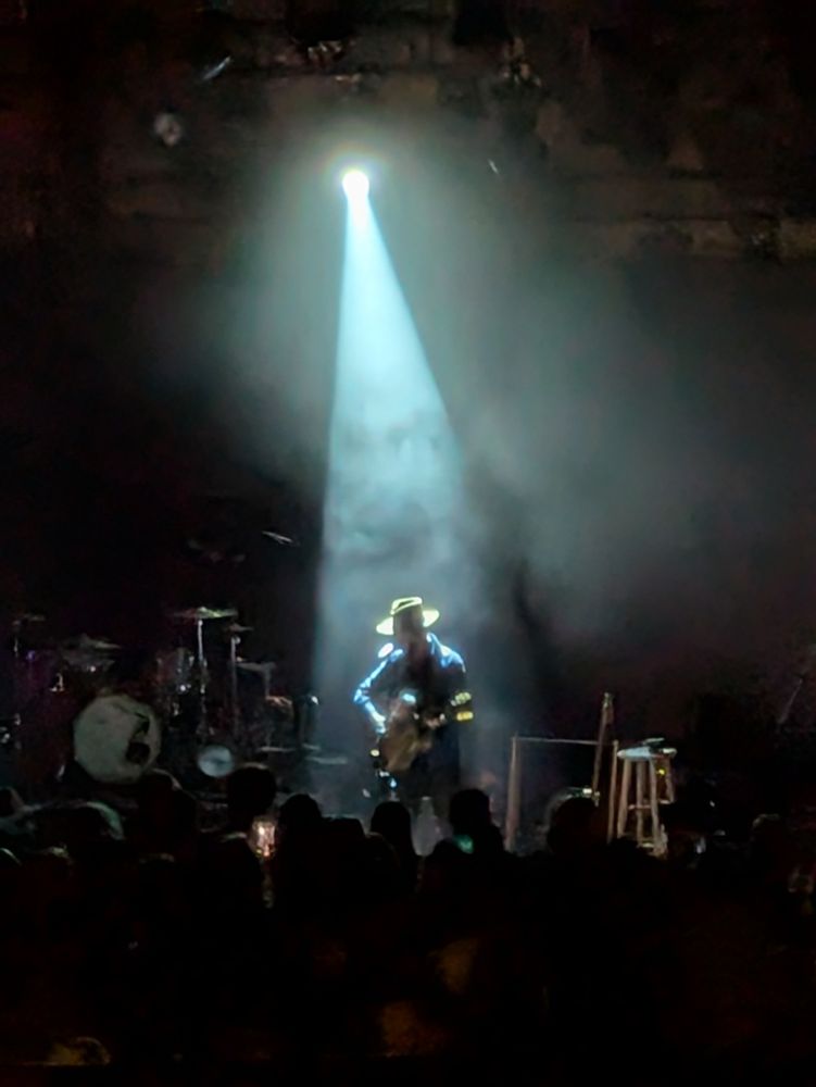 Singer, alone on a stage, backlit by a spotlight